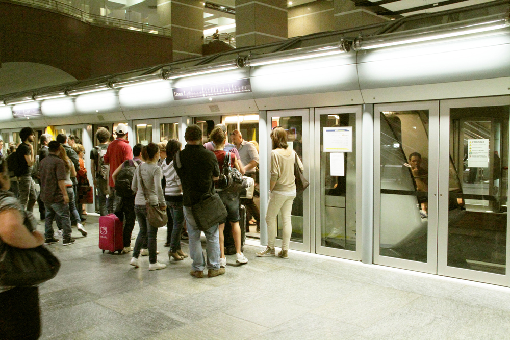 Passengers on subway platformm with doors between people and the train