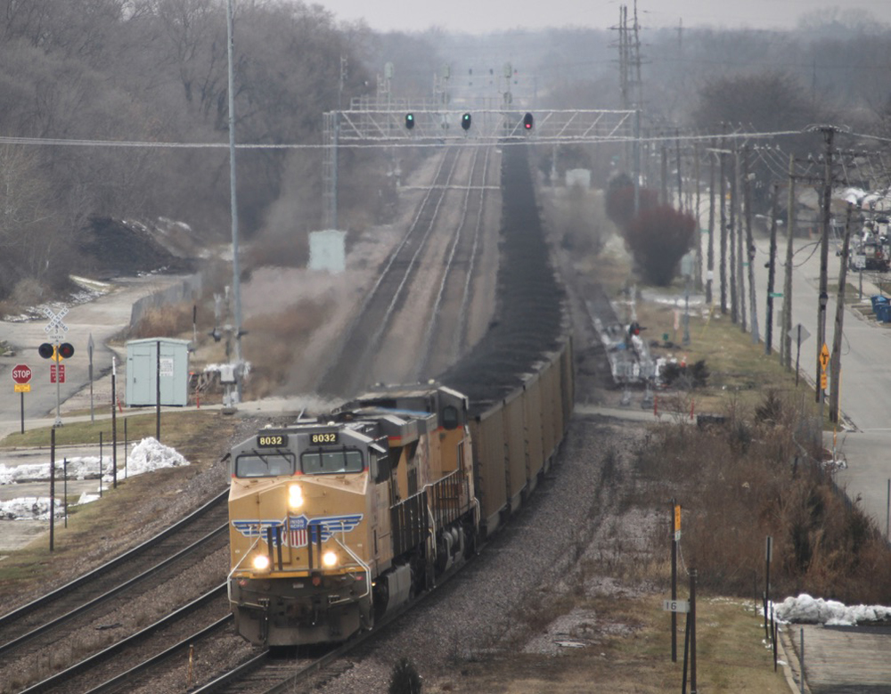 Train with yellow locomotives and coal hoppers on overcast day