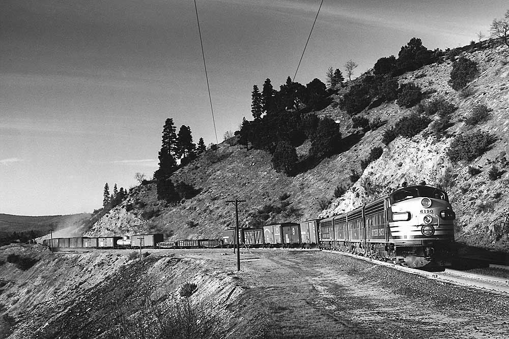 Streamlined diesel locomotives on freight train winding through curves on mountainside