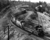 Five diesel locomotives lead freight train snaking through hills