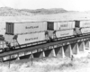 Early container train passes over low concrete bridge