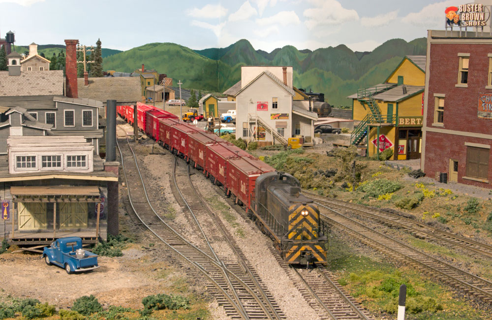 A green-and-yellow diesel pulls a train of red Swift Meats reefers