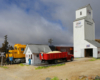 A young woman climbs the back of a grain truck on the scale at a grain elevator