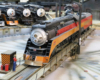 A steam locomotive in the Southern Pacific’s black, red, and orange “Daylight” scheme rides a turntable