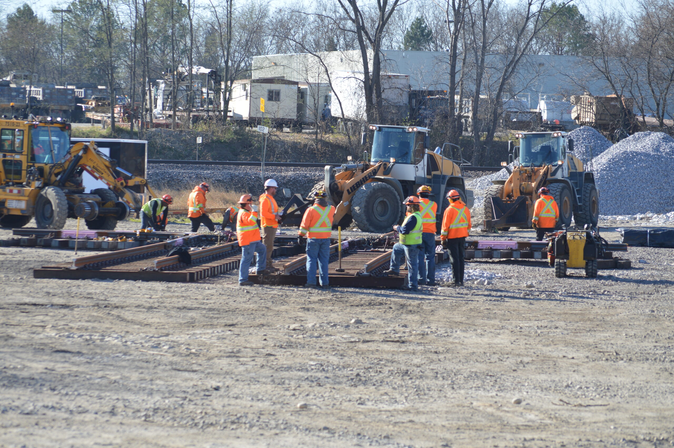 Workers in orange vests around the diamond crossing panel in the staging yard.
