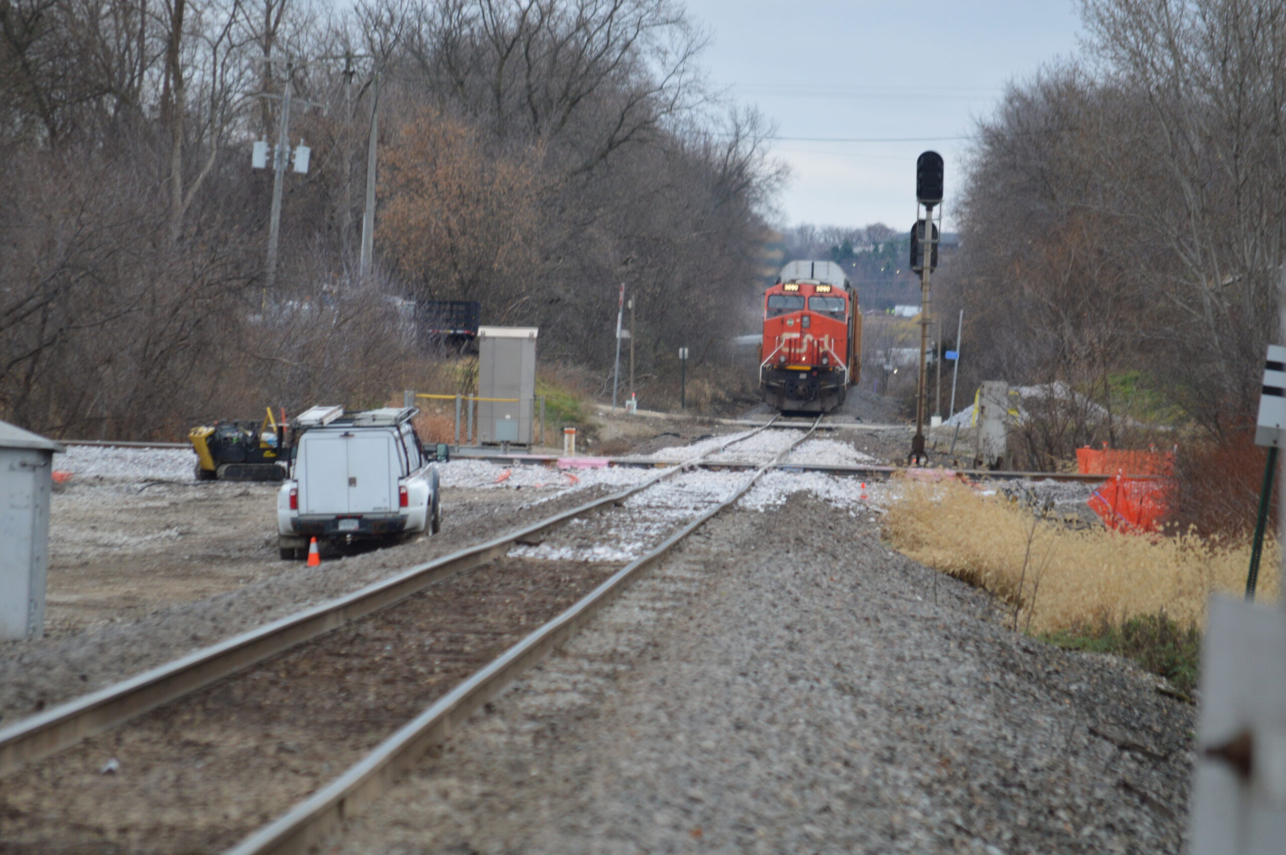 A red-nosed Canadian National diesel sits on the other side of the crossing where fresh ballast lays between the tracks.