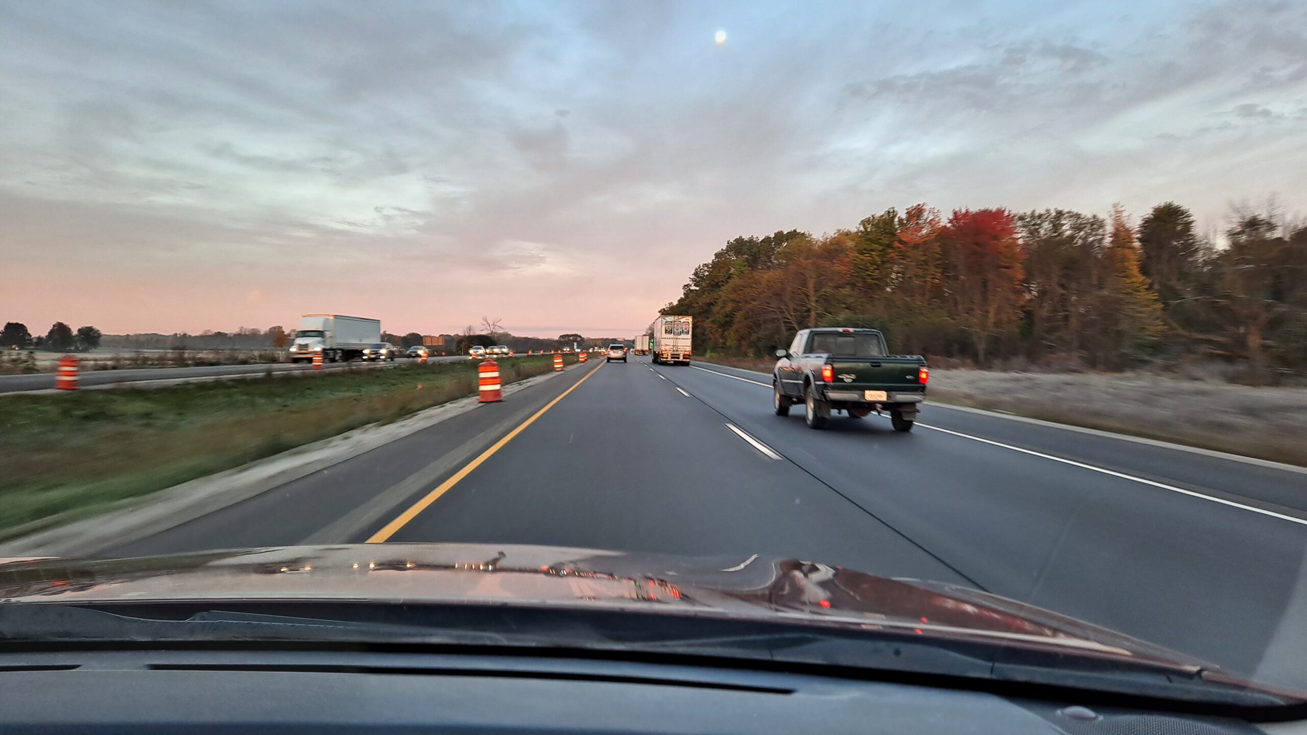 View of highway through windshield from passenger seat with morning traffic all around.