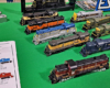 13 HO scale locomotives and shells are displayed on a green tablecloth.