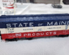 Red, white, and blue State of Maine boxcar with blue roof, white stripe in middle, red stripe at bottom, Bangor & Aroostook lettering in white band.