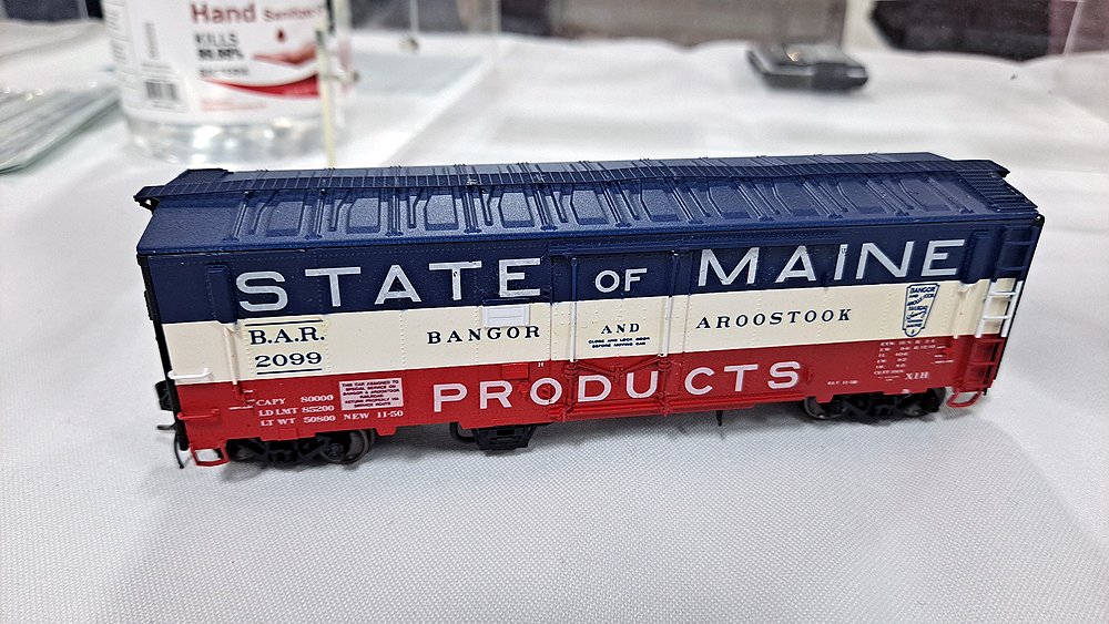 Red, white, and blue State of Maine boxcar with blue roof, white stripe in middle, red stripe at bottom, Bangor & Aroostook lettering in white band.