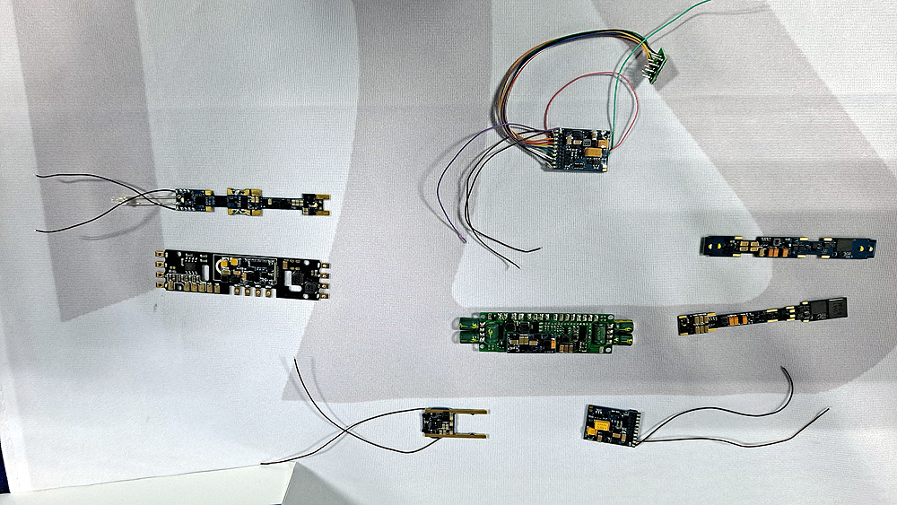 Eight Digital Command Control decoders, some with wire leads, on a white background.