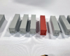 Seven gray and one brick red preproduction N scale container samples are shown on a white tablecloth.