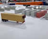 Yellow reefer container with brick red refrigerator casting on front, all mounted to container chassis.