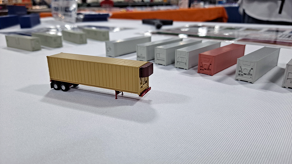 Yellow reefer container with brick red refrigerator casting on front, all mounted to container chassis.