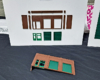 Structure walls and doors are mounted to a white board, with the assembled parts laying in front of the board on a table.