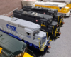Gray locomotive with blue CSX lettering, trucks, frame, and fuel tank.