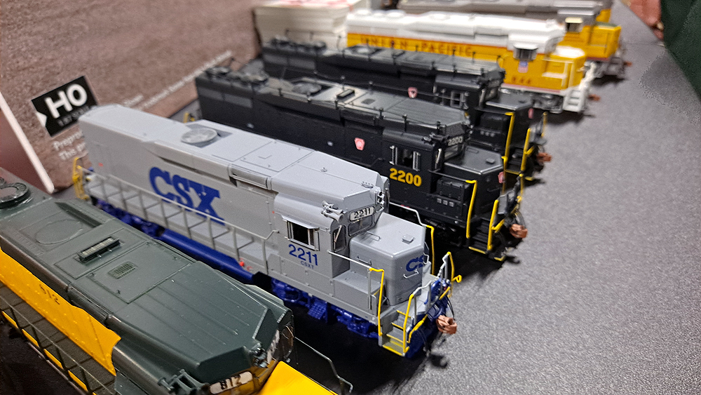 Gray locomotive with blue CSX lettering, trucks, frame, and fuel tank.