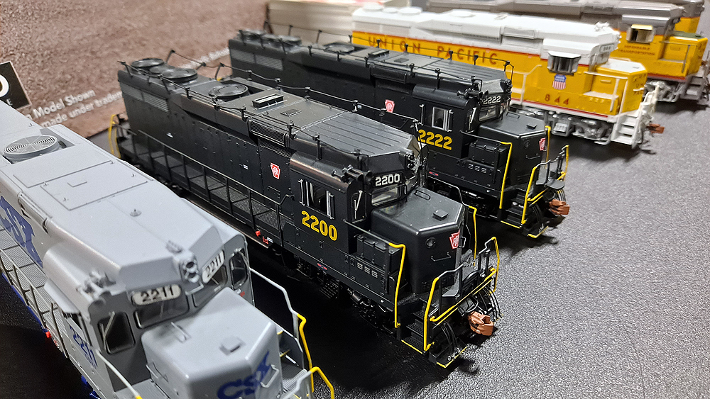 Dark green locomotives with yellow handrails and handrail-like antennas running along the roof.