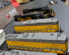 Cabless booster locomotives with darker gray roofs and yellow sides.