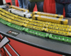 One row of green five-unit well cars sits in front of three rows of yellow five-unit well cars and for enclosed auto racks, three yellow and one white.