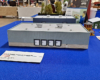 Gray and tan steel and concrete warehouse building on blue tablecloth.