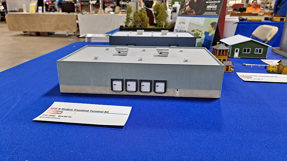 Gray and tan steel and concrete warehouse building on blue tablecloth.