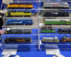 Nine EMD SD50s and four EMD NW2s are displayed on stepped clear plastic stands.