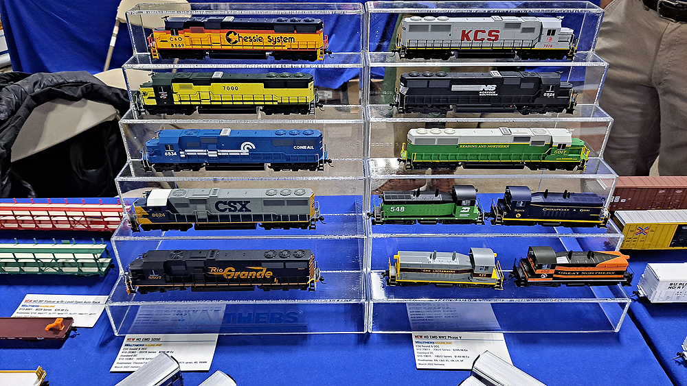 Nine EMD SD50s and four EMD NW2s are displayed on stepped clear plastic stands.