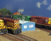 HO scale diesel locomotives, freight cars, and buildings on a scenicked layout.