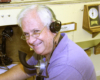 Don Ball model railroad images: Man wearing glasses smiling for photographer wearing breastplate transmitter and headset.