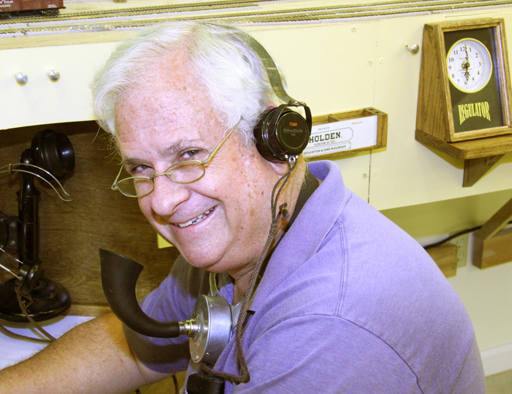 man wearing glasses smiling for photographer wearing breastplate transmitter and headset.
