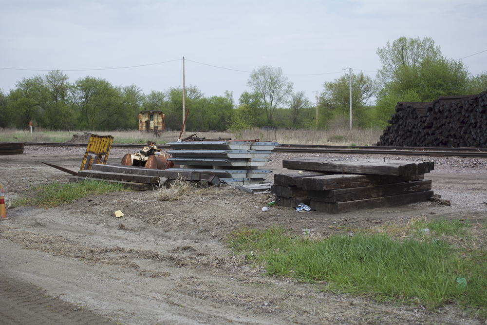 Stacks of concrete panels and wood planks for grade crossing near railroad tracks.
