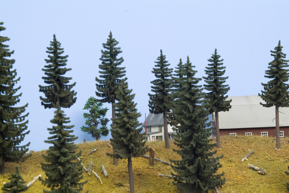 N scale barn and house partially obscured by HO scale trees.