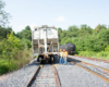 Two men in safety vests examine rerailed covered hopper