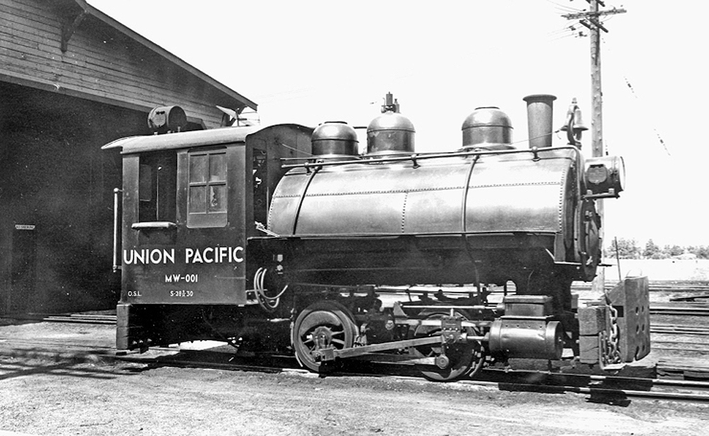 small black steam switcher parked next to building