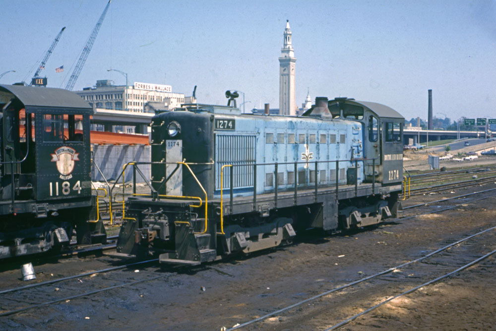 Ten unusual locomotive paint schemes: blue switcher locomotive next to black locomotive and two construction cranes in the background
