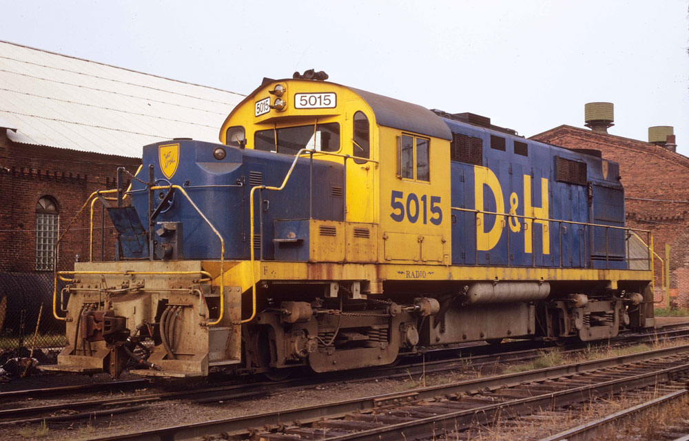 Ten unusual locomotive paint schemes: blue and yellow locomotive next to brown brick building