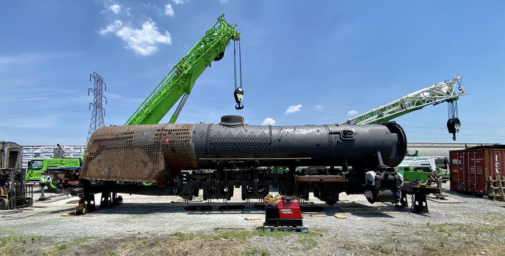 Portion of steam locomotive lifted by cranes