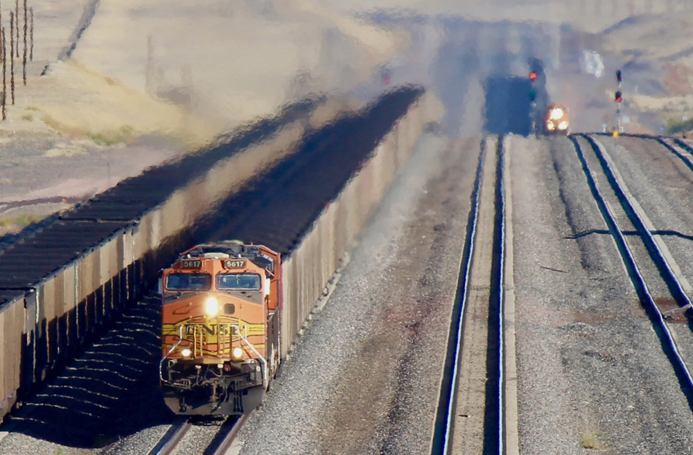 Coal train approaches with another visible in the distance