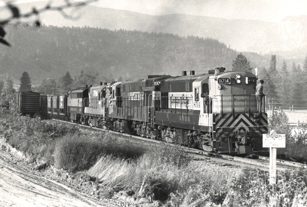Black and white photo of train in mountains with three diesels