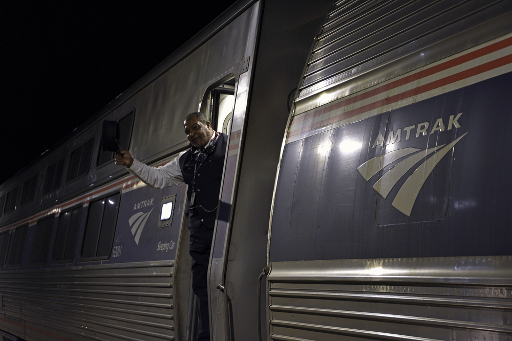 Conductor giving high ball signal at night with hat in hand.