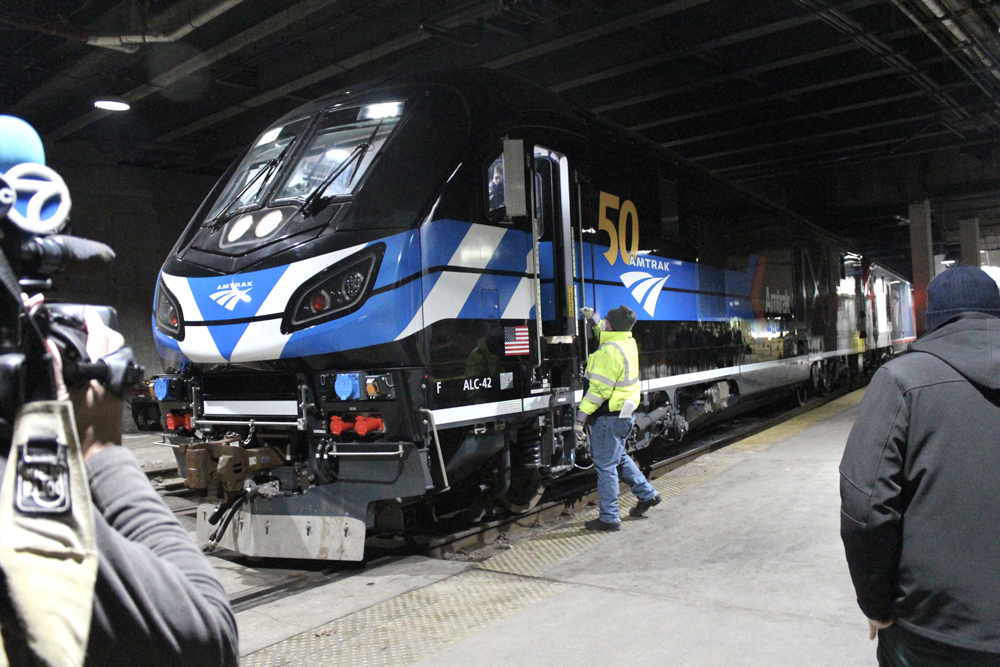 Black locomotive in station with RV cameraman in foreground