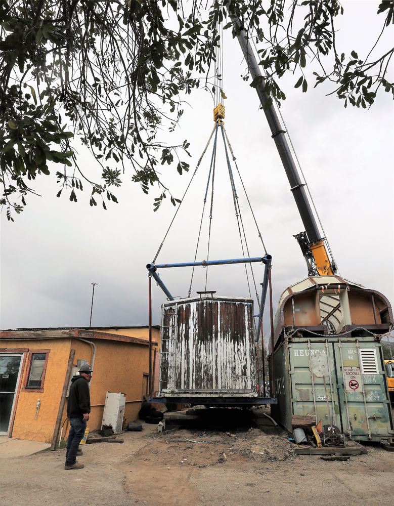 Wooden freight car being lifted by crane