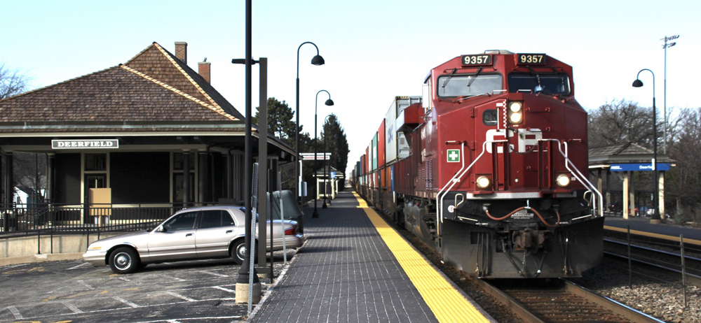 Train with red locomotive passing station