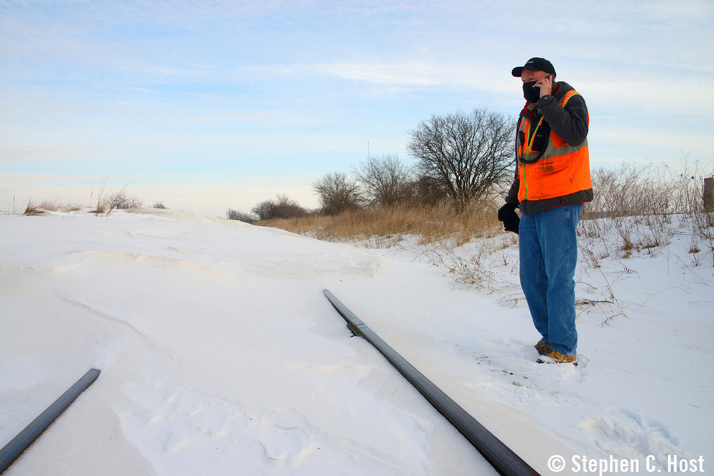 Man standing next to railroad tracks buried in snow