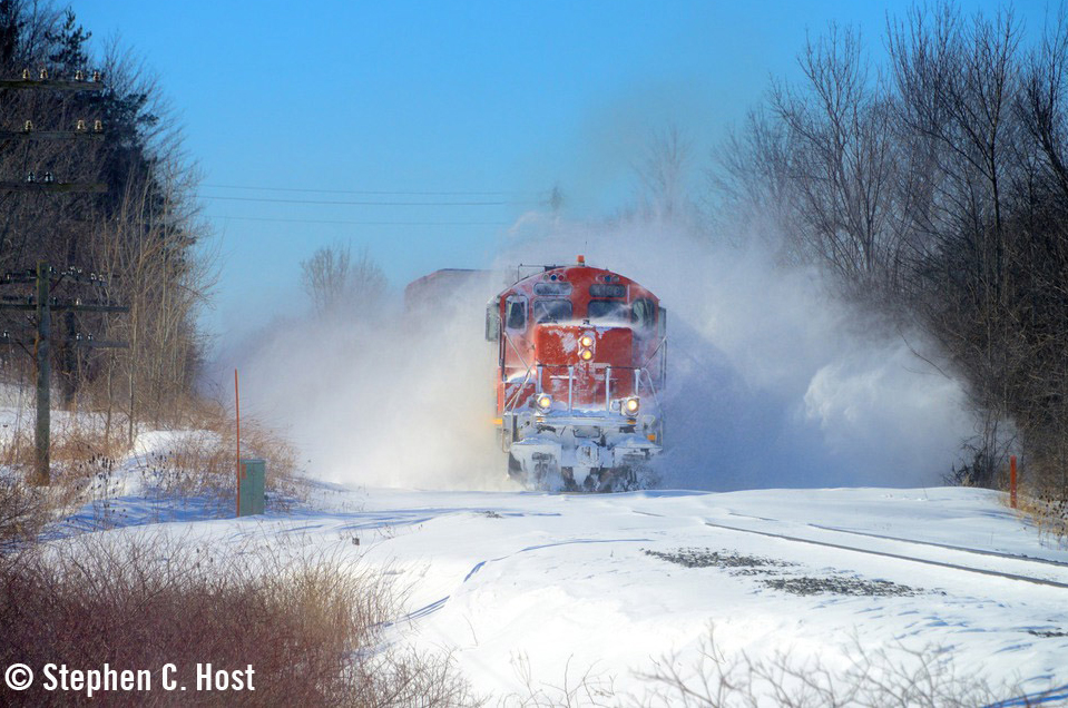 Train throwing snow as it pushes through drifts