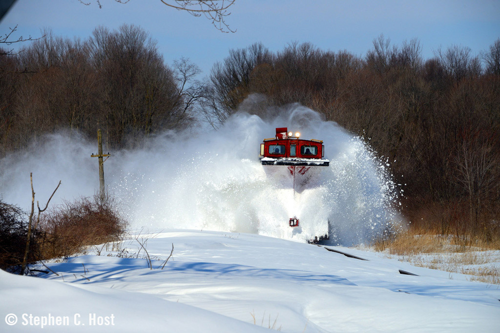 Wedge snowplow sends snow flying as it clears rail line