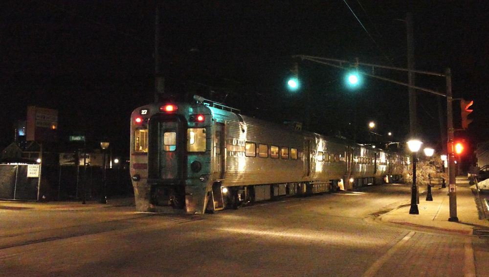 Electric multiple-unit commuter train running down street at night