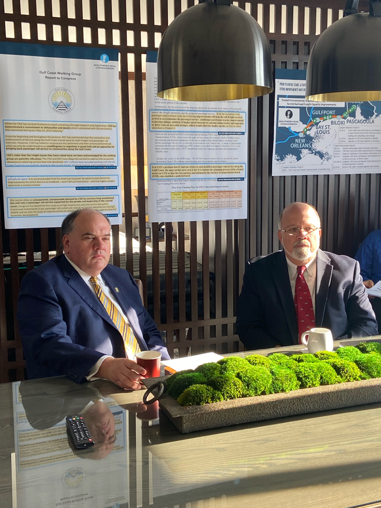 Two men at table with charts in background