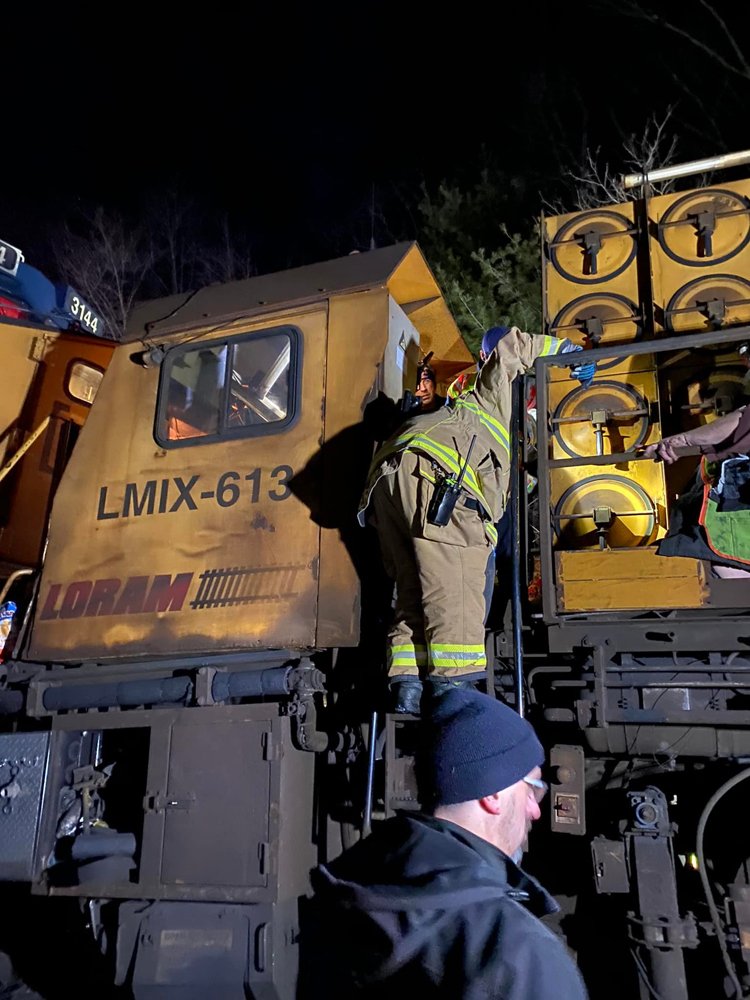 Firefighter climbs on to yellow rail equipment